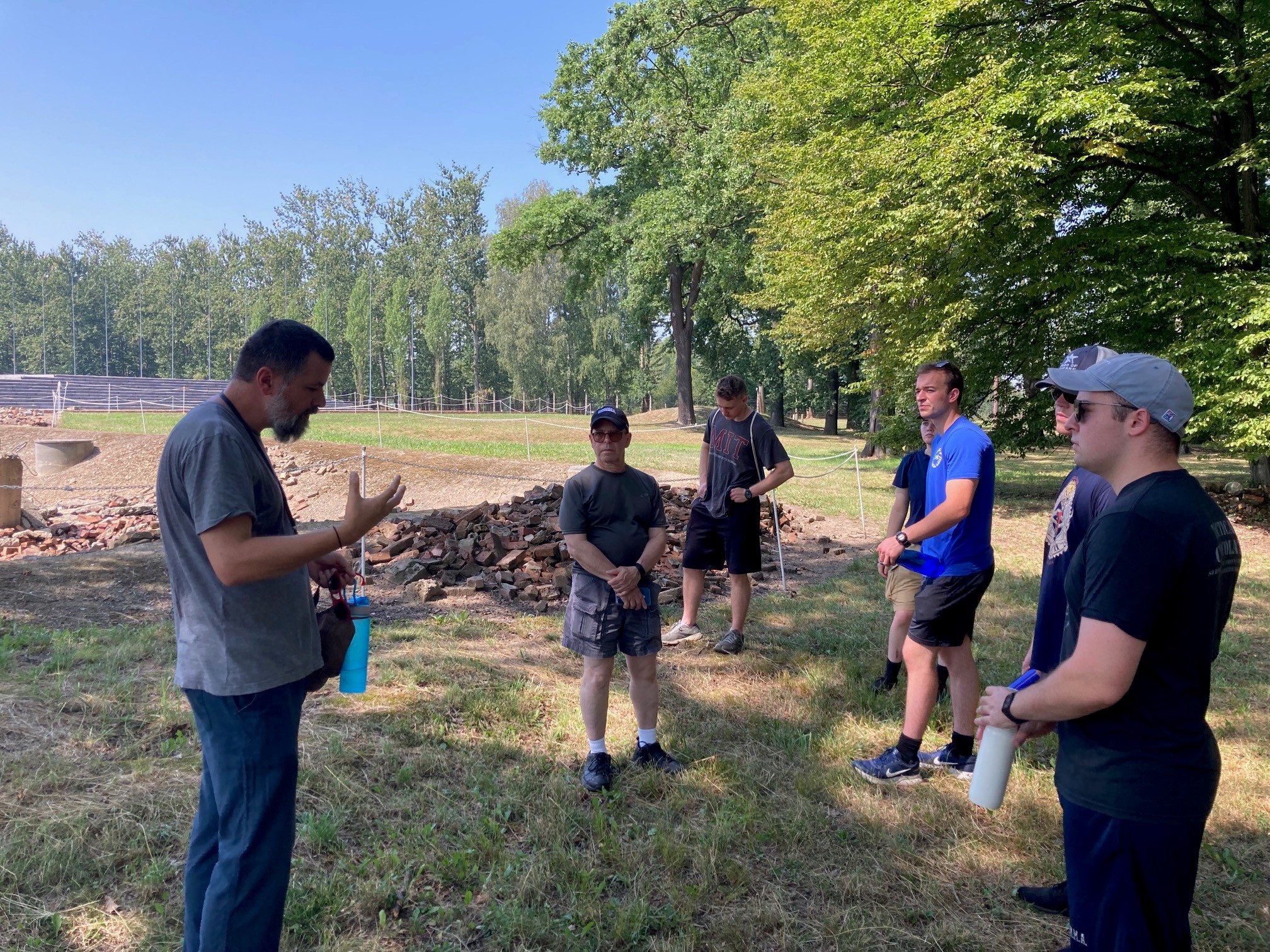 Students and Dr Melcer listen to the chief Auschwitz memorial guide, Pawel Sawicki, discuss one of the two Auschwitz 2 killing centers, seen in rubble behind them